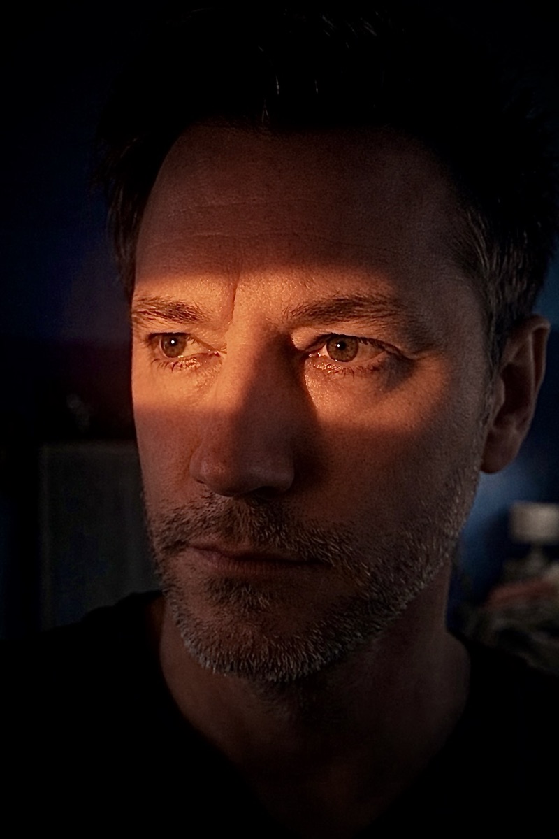 A close, warm, near-dark portrait of Fugdale staring straight down the lens.